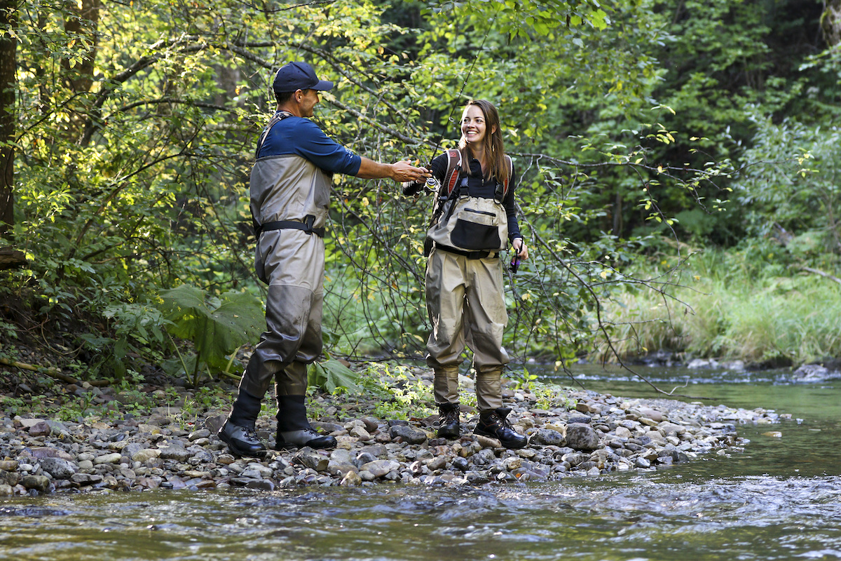 Man-and-woman-fly-fishing-on-a-river-wearing-waders