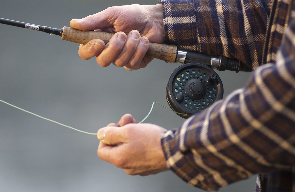Man holding a fly rod and reel in his hands