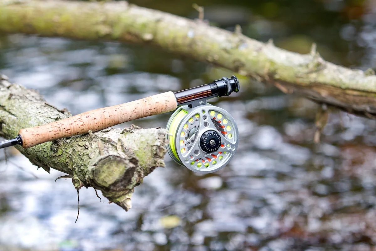 Rod-with-a-fly-reel-attached-balanced-on-a-stick-above-a-river