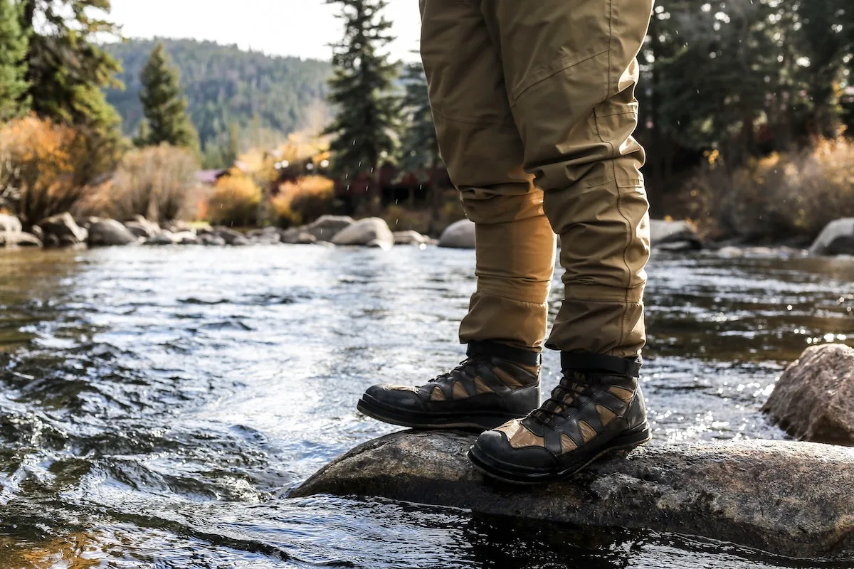 The legs of a fly fisherman standing on rocks