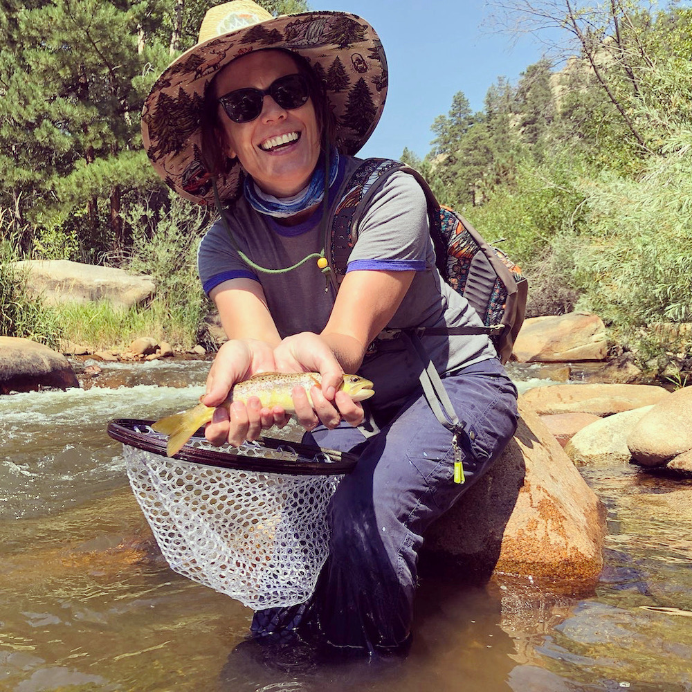 Woman holding a fish above a net after fly fishing