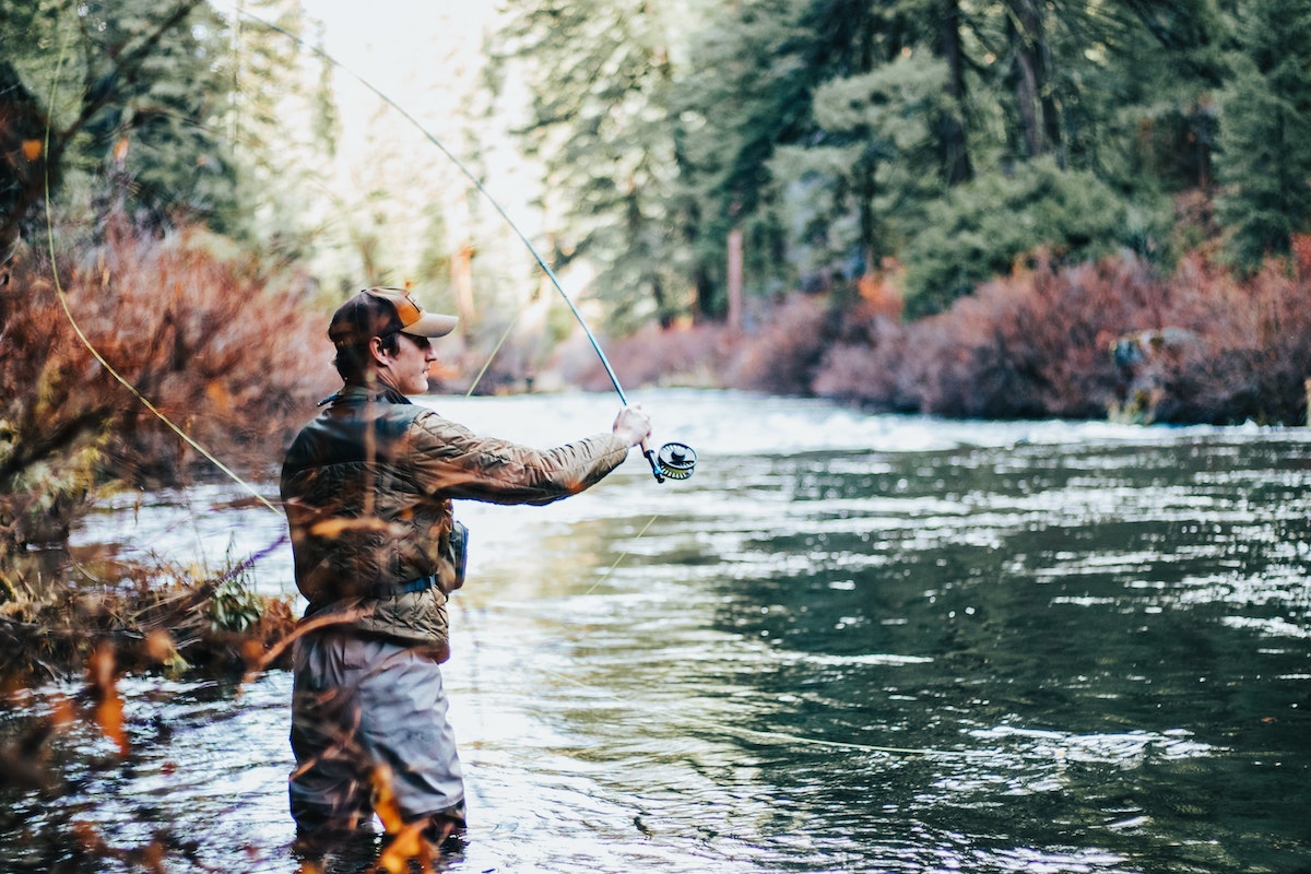 Man casting a fly fishing rod on a fall day
