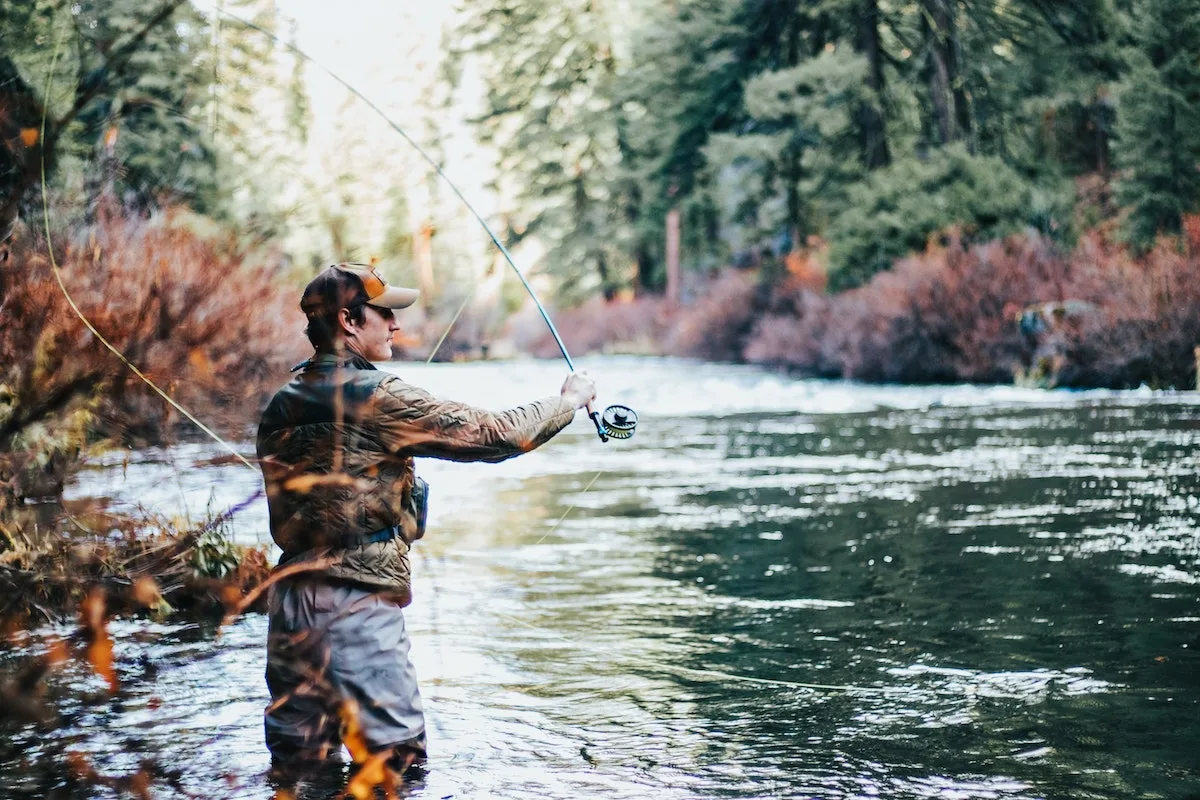 Man casting a fly fishing rod on a fall day
